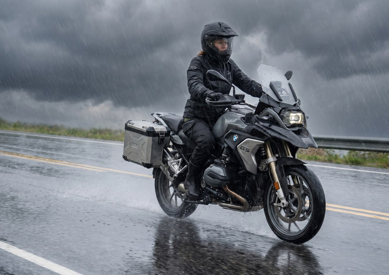 Woman riding an adventure motorcycle in heavy rain in the RoadArmor Women's pants