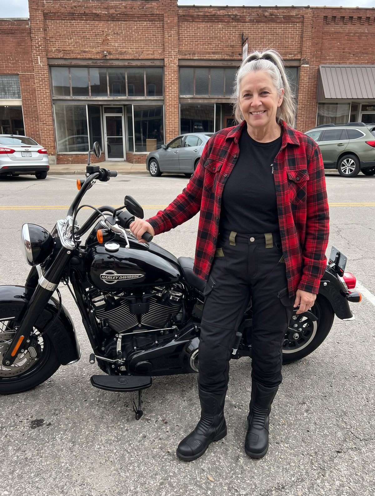 Woman rider in her 60s beside her Harley Heritage in the black RoadArmor Women's pants